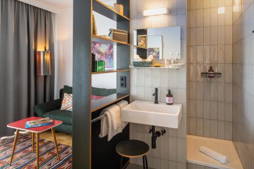 a small bathroom with a sink and a chair at magdas HOTEL Vienna City - First Social Business HOTEL in Austria in Vienna
