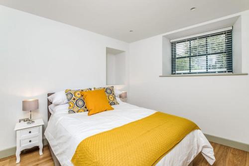 a white bedroom with a bed with a yellow blanket at Hawkers Padstow in Padstow