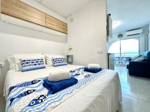 1 dormitorio con 1 cama grande con almohadas azules y blancas en Face a la Mer - vue epique, climatisation, wifi, draps inclus, en Empuriabrava