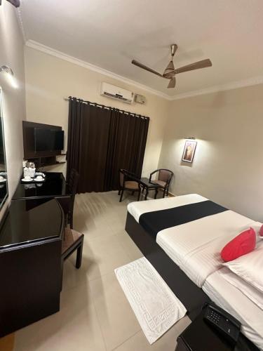 a bedroom with a bed and a desk and a television at GD International Redfort in Nilambūr