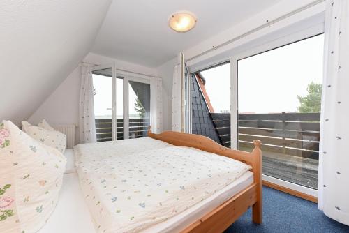 a bedroom with a bed and a large window at Ferienhaus Am Tief in Neuharlingersiel