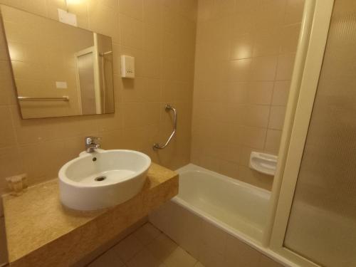 een badkamer met een wastafel en een bad bij The San Anton Hotel in St Paul's Bay