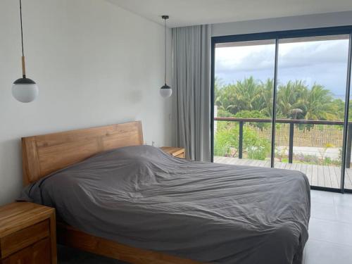 a bedroom with a bed and a large window at Villa lagoon view Baie du cap bel ombre in Baie du Cap