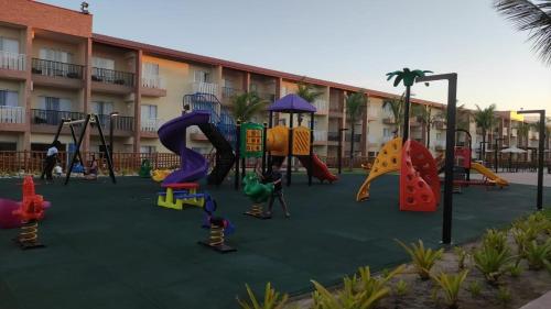 un parque infantil frente a un hotel con toboganes y columpios en Ondas Praia Resort en Porto Seguro