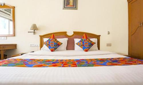 a bedroom with a large white bed with colorful pillows at FabHotel Altus in Gurgaon