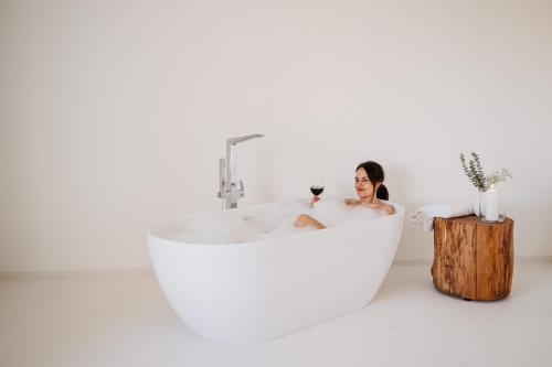 a woman sitting in a bath tub in a white bathroom at REZAVY in Mikulov