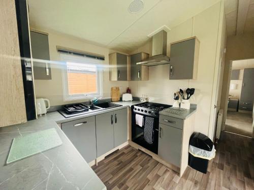 a small kitchen with a stove and a sink at Pine Lodge with Hot Tub in York