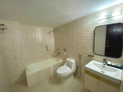 uma casa de banho com um WC branco e um lavatório. em Hotel Valentino em Noākhāli
