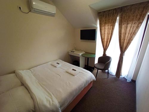 a hotel room with a bed and a chair and a desk at Vila Astonia in Subotica