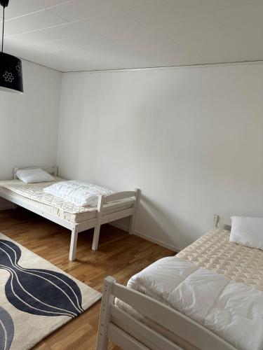 two beds in a room with white walls and wooden floors at RFM Tingsryd in Tingsryd