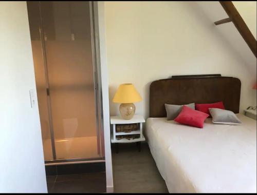 a bedroom with a bed with red pillows and a lamp at SGDB in Sainte-Geneviève-des-Bois