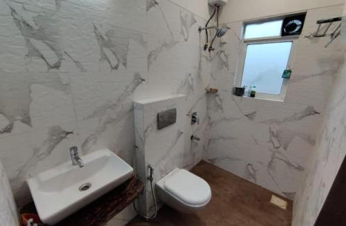 a white bathroom with a sink and a toilet at Ivy Zen 1 BHK with Common Pool 12 kms from Imagicaa in Jambhulpāda