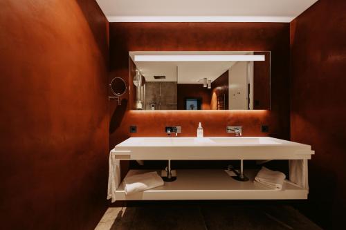 Guesthouse Suiteseven في ميرانو: حمام مع حوض ومرآة