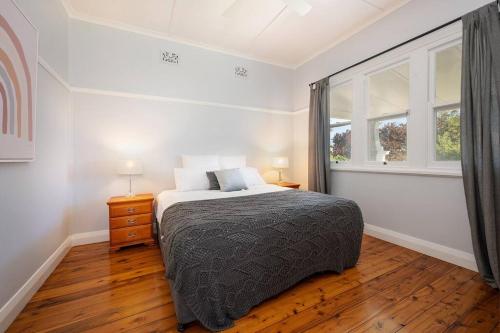 a white bedroom with a bed and a window at Brightly Cottage in Mudgee
