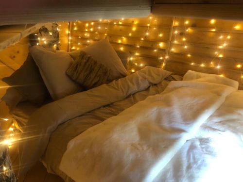 ein großes weißes Bett mit Beleuchtung in der Unterkunft Nuit insolite - La cabane du Haut-Doubs in Les Gras