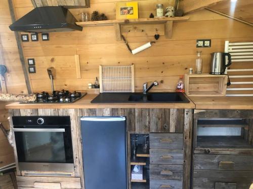 cocina con encimera con fregadero y TV en Nuit insolite - La cabane du Haut-Doubs, en Les Gras