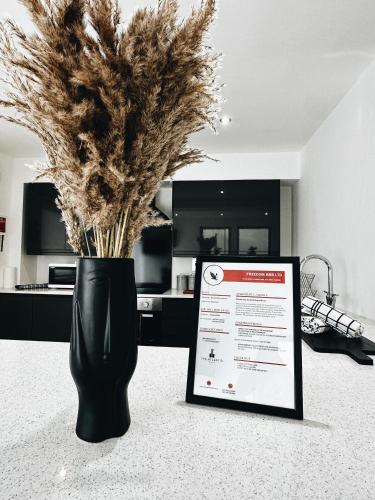 a black vase with some dry grass in a room at The Atlantis - Tower Apartments in Great Yarmouth