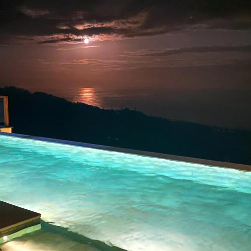 a swimming pool with a view of the ocean at night at Umarato Villa Sumba in Rua