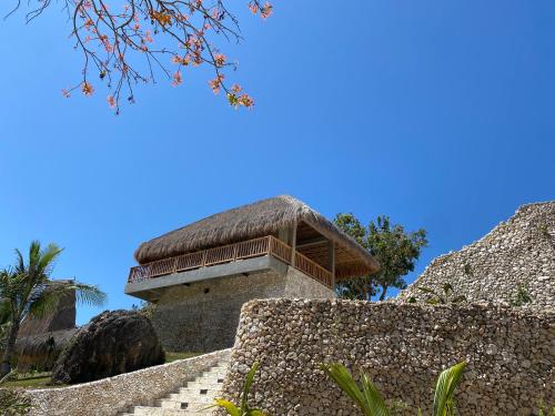 a building with a thatch roof on top of a stone wall at Umarato Villa Sumba in Rua
