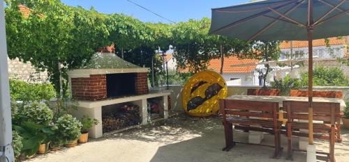 a patio with a brick fireplace and a table and an umbrella at Guesthouse Lidija in Sutivan