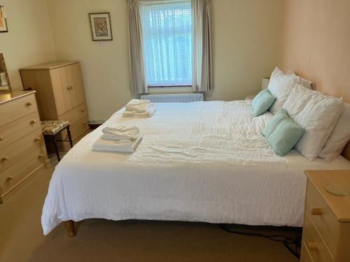 a bedroom with a large white bed with blue pillows at Bide-a-While in Marnoch