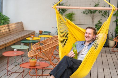 a man sitting in a yellow hammock holding a beer at magdas HOTEL Vienna City - First Social Business HOTEL in Austria in Vienna
