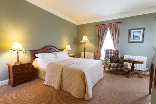 a bedroom with a bed and a table and a chair at Sheedys Boutique Hotel & Restaurant in Lisdoonvarna