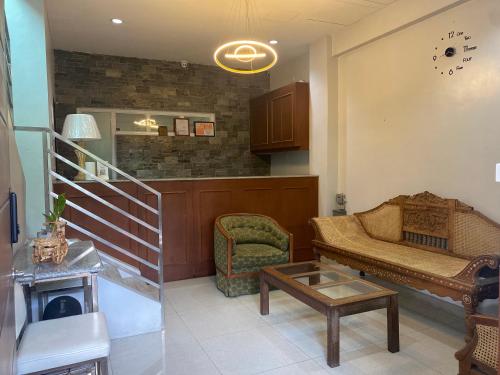 a living room with a staircase and a couch and a chair at ABE Lodge Taguig in Manila