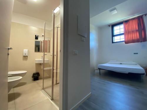 a bathroom with a bed and a glass shower at Ostello di Vicenza in Vicenza