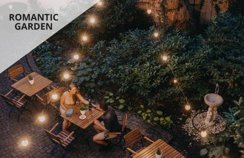 un groupe de personnes assises à une table dans un jardin dans l'établissement Hotel Adler - Czech Leading Hotels, à Prague