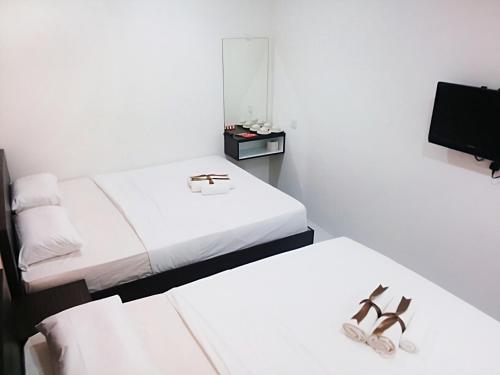 a white room with two beds and two pairs of shoes at Hotel Checkedinn in Ipoh