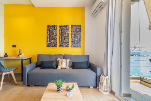 a living room with a blue couch and a yellow wall at Luxury SeaSide Suites in Hersonissos