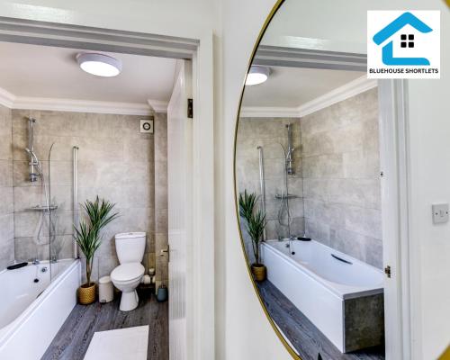 a bathroom with a tub and a toilet and a mirror at Great Location, Ideal Place for your December Stay, Close to the beach, station and restuarants, Cosy House l by Bluehouse Short Lets Brighton in Brighton & Hove