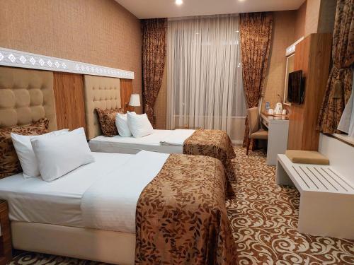 a hotel room with two beds and a desk at Graaf Hotel in Baku