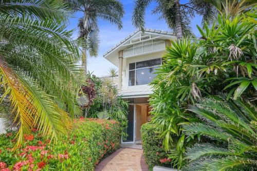 a house with palm trees and plants in front of it at Grand Slam Getaway with Tennis Court and Heated Pool in Kewarra Beach