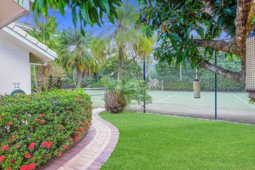 a tennis court with flowers and a tennis racket at Grand Slam Getaway with Tennis Court and Heated Pool in Kewarra Beach