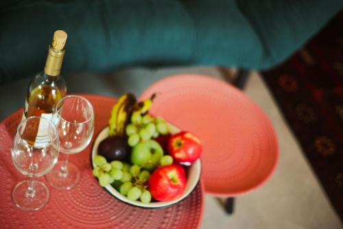 a red table with a bowl of fruit and a bottle of wine at MARRAKECH פלא - PELEH - Queit place 3 km from the beach of Cesarea in Or ‘Aqīvāh