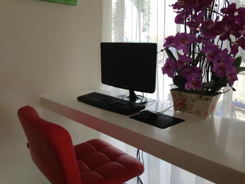 a desk with a computer and a vase of flowers at Hotel Checkedinn in Ipoh