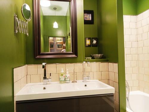 ein grünes Bad mit einem Waschbecken und einem Spiegel in der Unterkunft A Vol D'Oiseau in Honfleur