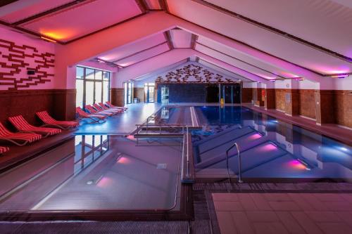 a large swimming pool with purple lighting in a building at Ruskovets Thermal SPA & Ski Resort in Bansko