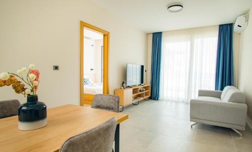 a living room with a table and a couch and a television at Royal Blue Resort & Residences in Tivat