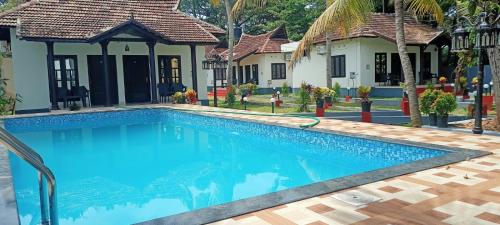 a swimming pool in front of a villa at Winterfeel Resort in Alleppey