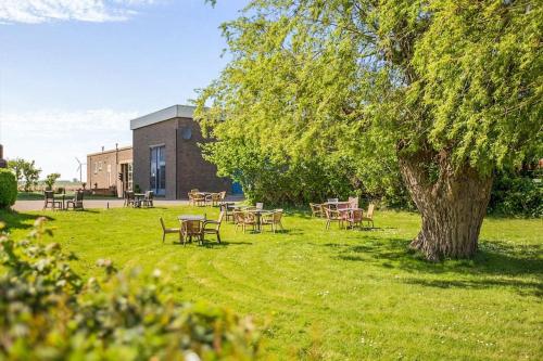 a group of tables and chairs under a tree at Groeps-, Retreat- en Trainingsaccomodatie De Waterkroon! in Wieringerwaard