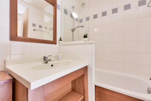 a bathroom with a sink and a tub and a mirror at Residence Les Grands Pins - maeva Home in Carcans