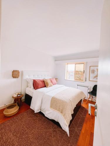 a white bedroom with a large white bed with red pillows at Just Like Home - Blue River in Caminha