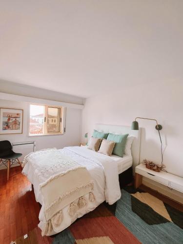 a white bedroom with a large white bed with pillows at Just Like Home - Blue River in Caminha