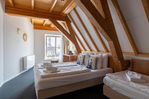 two beds in a room with wooden ceilings at Hotel Stad aan Zee Vlissingen in Vlissingen