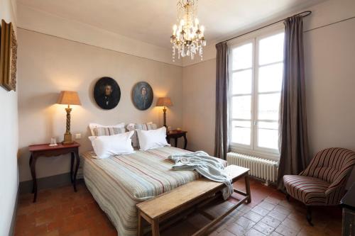 a bedroom with a bed and a chair and a window at Commanderie de Peyrassol in Flassans-sur-Issole