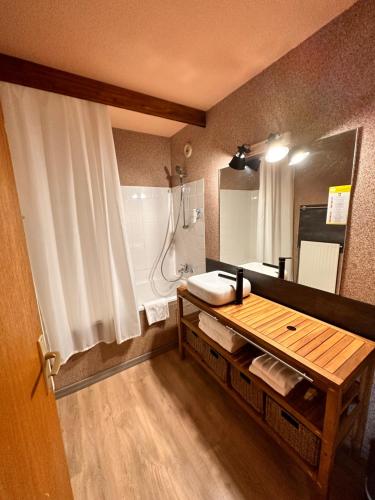 uma casa de banho com um lavatório e um chuveiro com um espelho. em Fontaine du Mont Blanc Hotel & Spa em Les Houches
