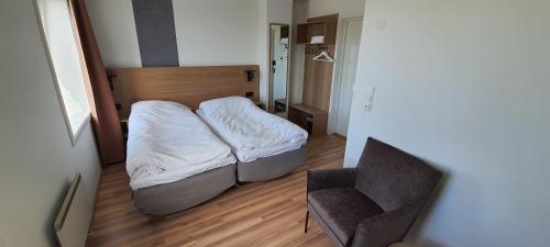 um pequeno quarto com uma cama e uma cadeira em Systra Hotel Søvik em Syvik